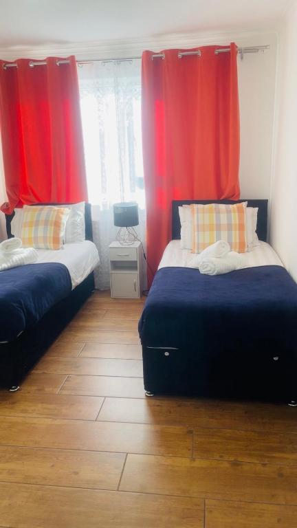 two beds in a room with red curtains at Cozy plaza lodge in Rochester