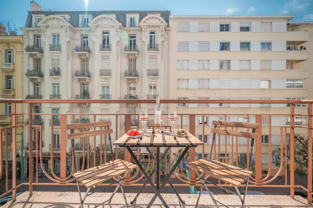 a table and chairs on a balcony with a building at Le COQ Edouard VII - Parking - Proche mer in Menton