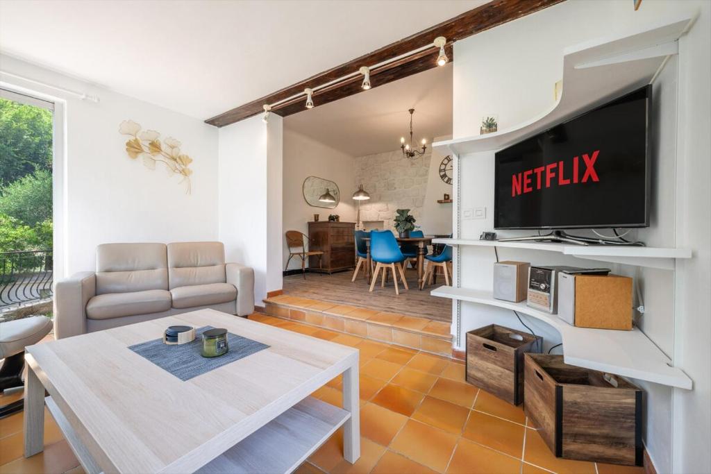 a living room with a television and a table at Le Coq Saint-Jean - Parking - WiFi - Reposant in Gorbio