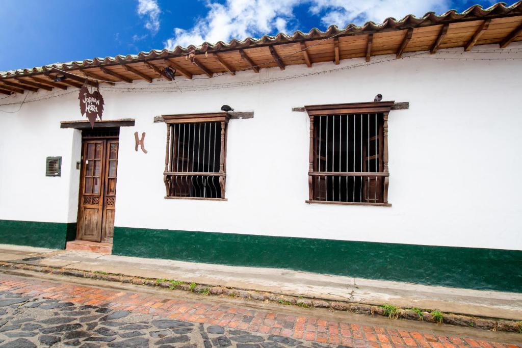 un edificio blanco con tres ventanas y una puerta en Hotel Jordan, en Guaduas