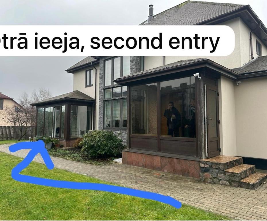 a house with a screened in porch with a blue arrow at Hugo Airport in Mārupe
