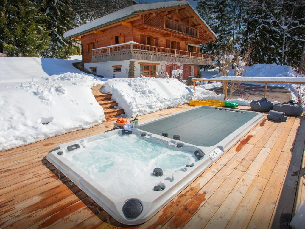 a hot tub on a deck in front of a house at Chalet Le Mousqueton - OVO Network in La Clusaz