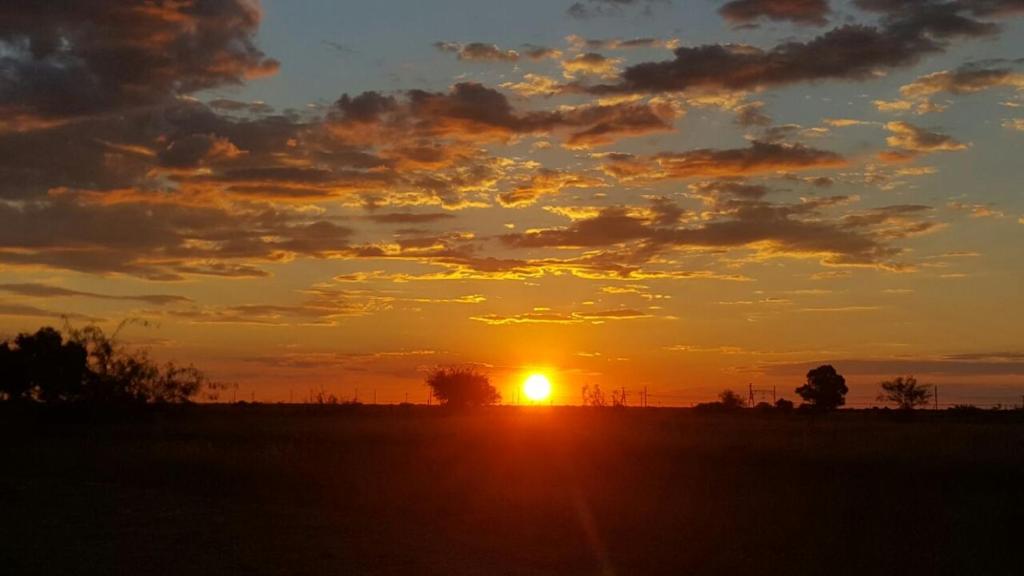 a sunset in a field with the sun in the sky at Bloemhof Riverside Chalets 