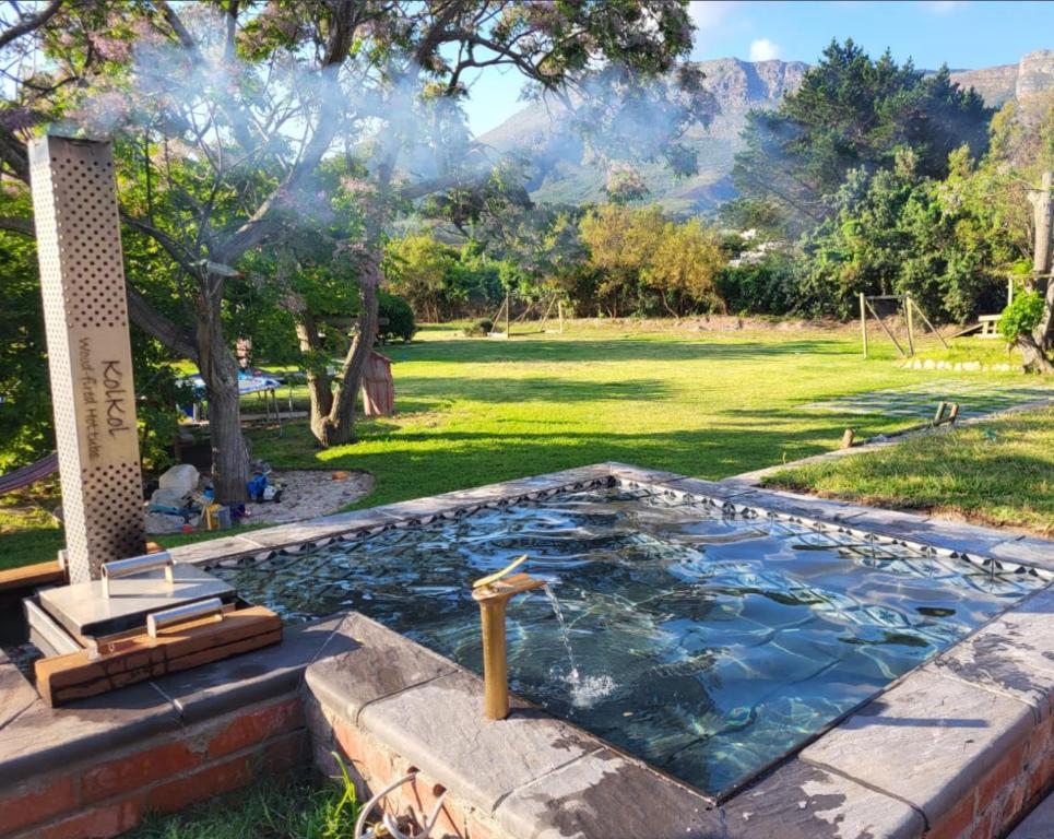 een zwembad in een tuin met een berg op de achtergrond bij Villa Kenali in Noordhoek