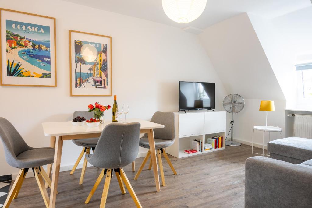 Una sala de estar con una mesa y sillas y un televisor. en Kaisercity Apartment 3, en Núremberg