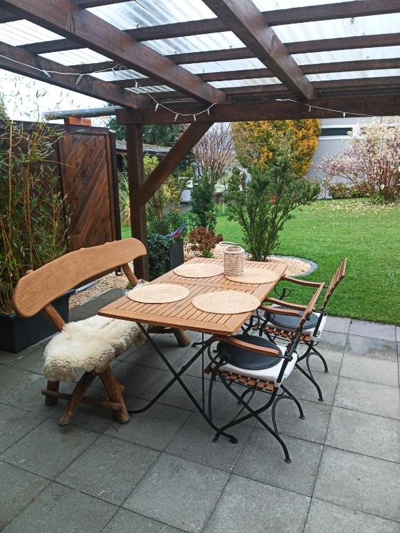 埃申Garten-Wohnung的凉棚下的一张木桌和椅子