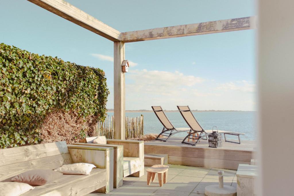 twee stoelen en een bank op een terras met uitzicht op de oceaan bij Dijkvilla - 6 personen in Holle Poarte