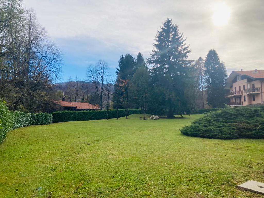 a large grassy field with a house and trees at Chalet Nausicaa in Lanzo dʼIntelvi