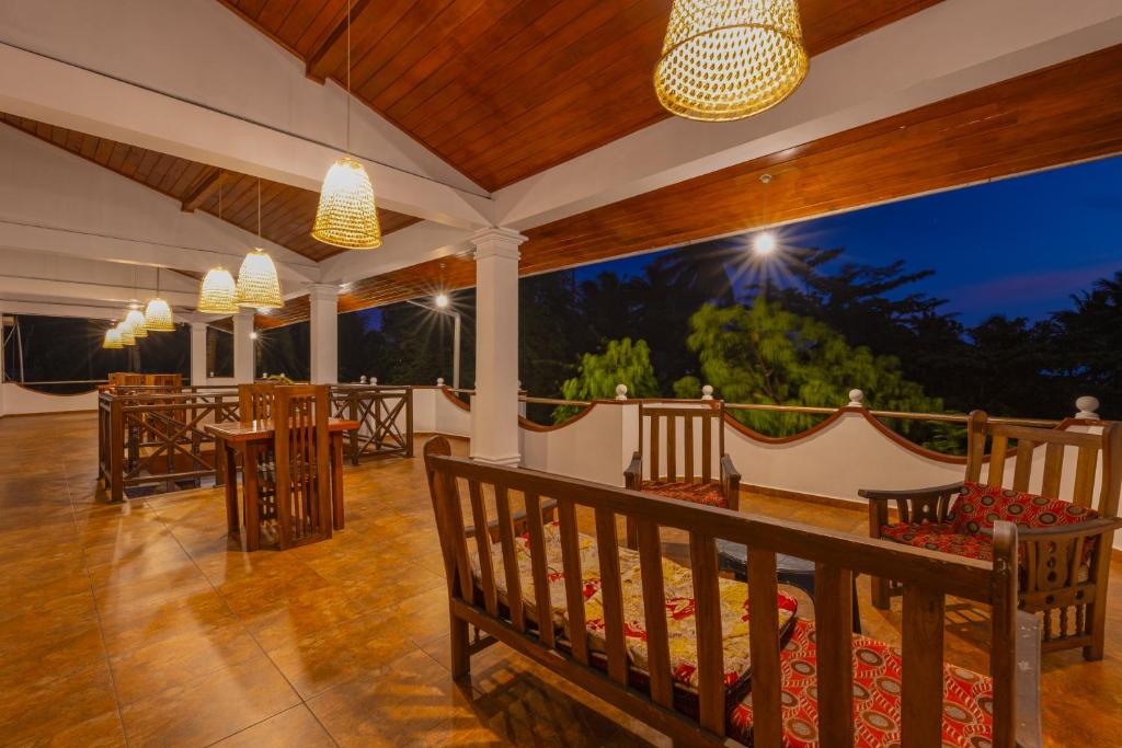 a porch with tables and chairs and lights at Serendipity Beach Hotel in Unawatuna