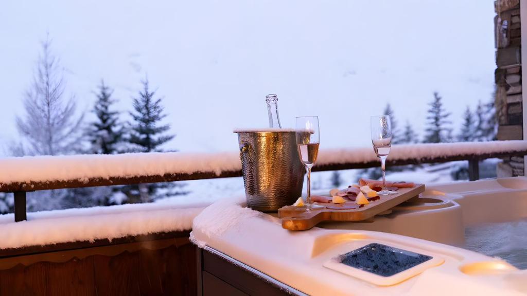 a table with two glasses of wine and a plate of food at Chalet Vithos - Luxe, ski aux pieds in Les Bruyères