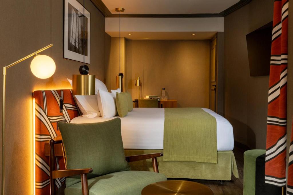 a hotel room with a bed and two chairs at Hôtel Louvre Piemont & Spa in Paris