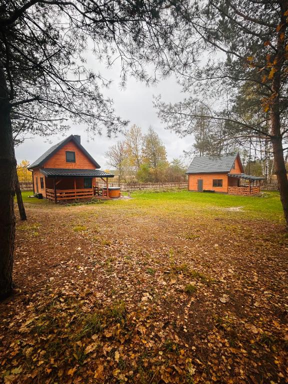 two buildings in a field with trees and a yard at Bolek i Lolek domki do wynajęcia in Popielżyn Dolny