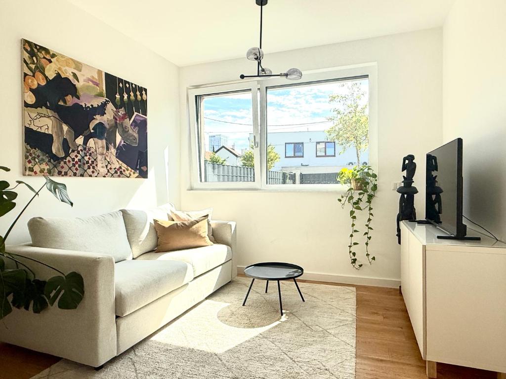 uma sala de estar com um sofá branco e uma janela em Modern Studio Gardenia_Gartenwohnung Alte Donau em Viena