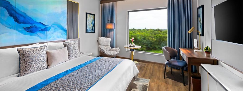 a hotel room with a bed and a desk and a window at Fortune Select Siliguri in Binnāguri