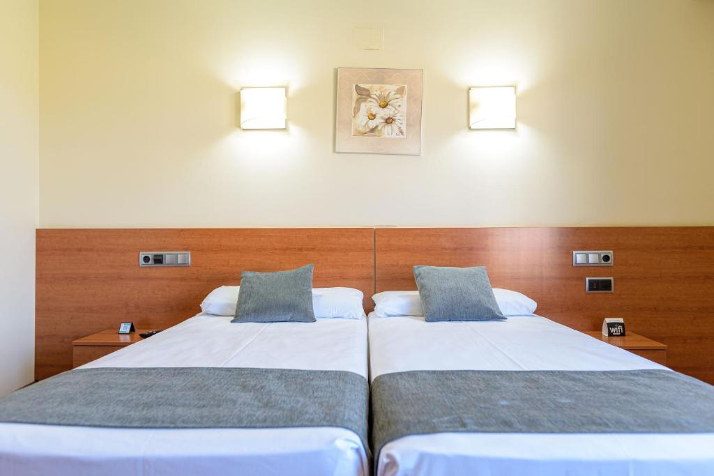 トロにあるAlda Plaza Mayor Toroのベッド2台 ホテルルーム 壁に照明付