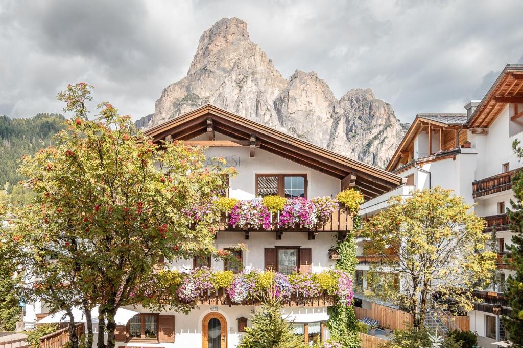 a building with flowers in front of a mountain at Villa Resi Apartments in Corvara in Badia