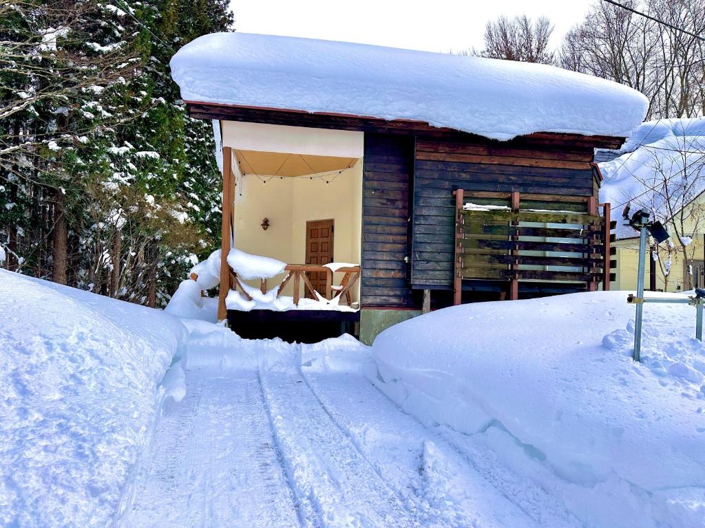 a small house covered in snow next to a pile of snow at 東京2時間スキー場徒歩3分温泉付 友達や家族と一棟貸 in Sudagai