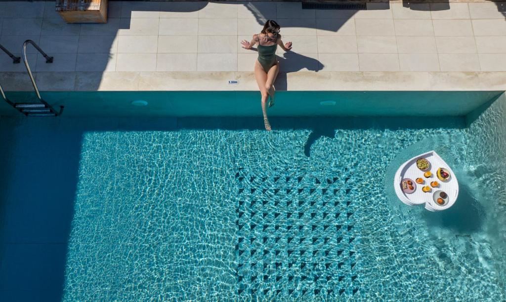 a woman standing in a swimming pool next to a swimming pool at Villa Arancia in Pigi