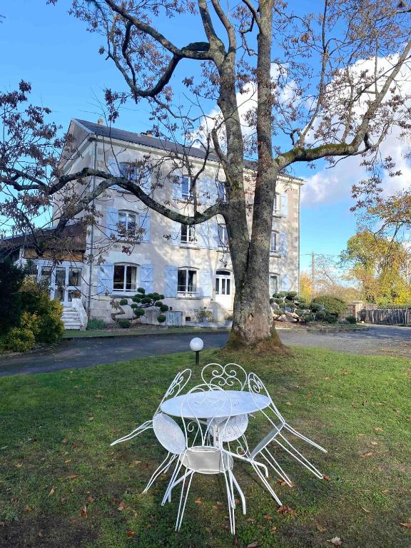 a table and two chairs in front of a tree at Le Moulin Du Port in Saint-Georges-sur-Cher