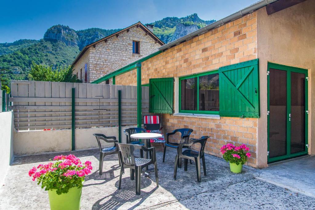a patio with a table and chairs and flowers at Le chardon à blajoux in Montbrun