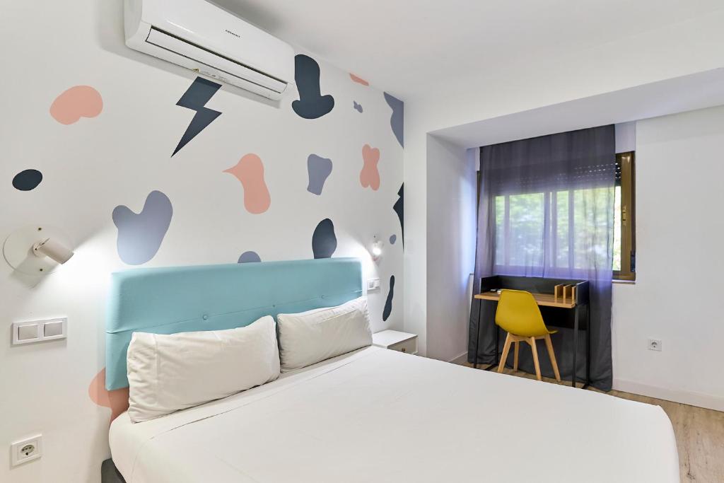 a bedroom with a white bed and a yellow chair at Hostal Carmen by gaiarooms in Salamanca