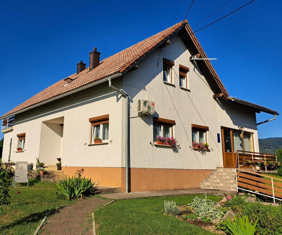 een wit huis met ramen en een dak bij Guesthouse Zafran in Smoljanac