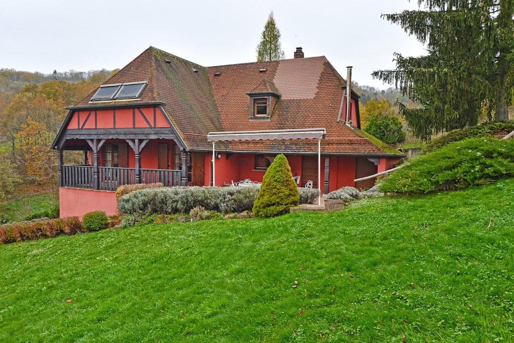 une maison rouge au sommet d'une colline verdoyante dans l'établissement Chalet Les Terrasses d'Albé 6P Montages & Vignes, à Albé