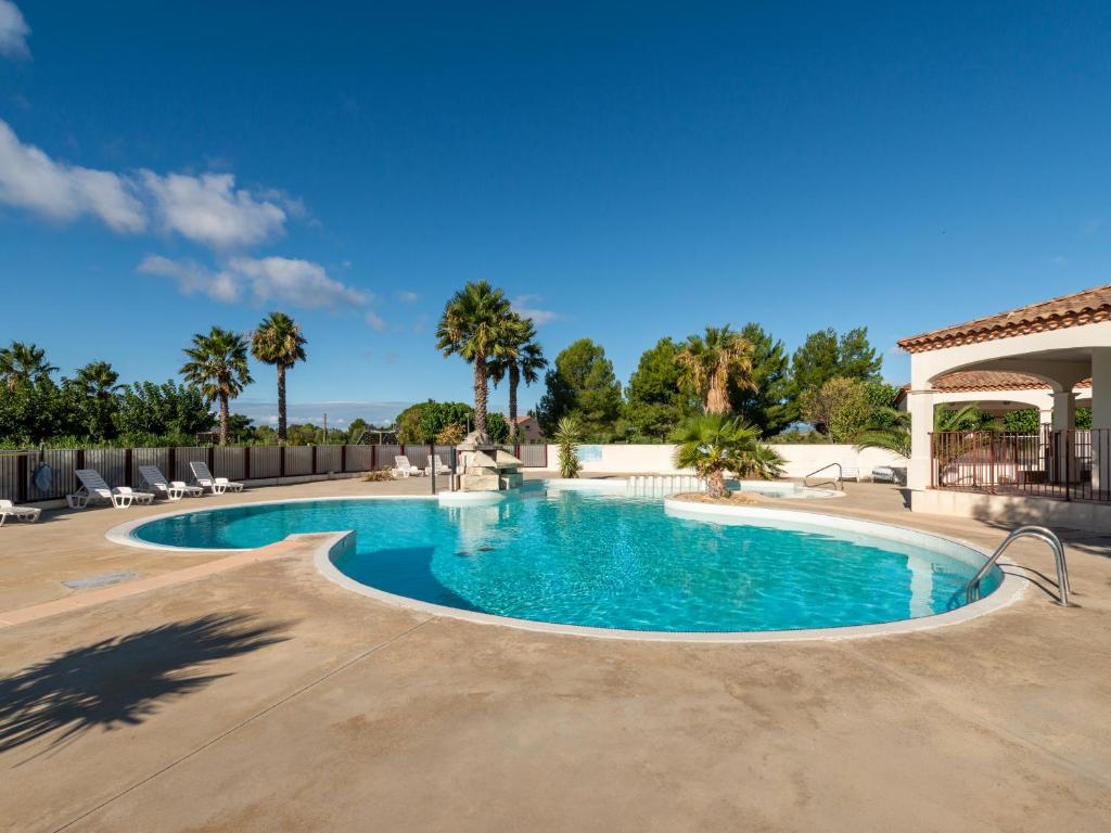 a swimming pool in a resort with palm trees at Vacancéole - Port Minervois, Les Hauts du Lac in Homps
