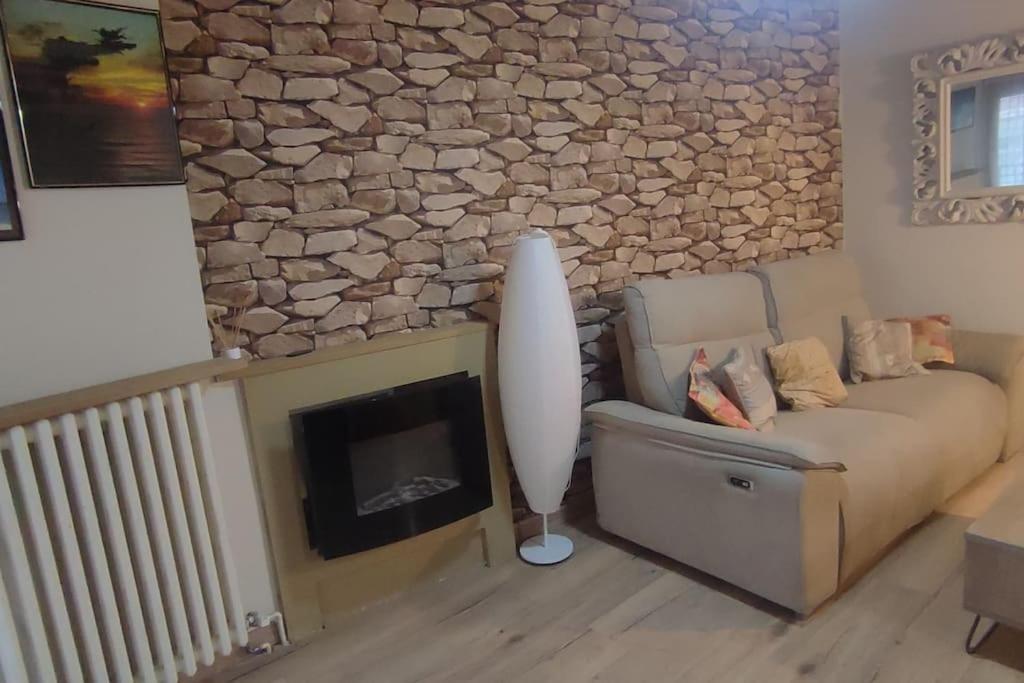 Una sala de estar con un sofá y una pared de piedra. en La torre romana, en Olite