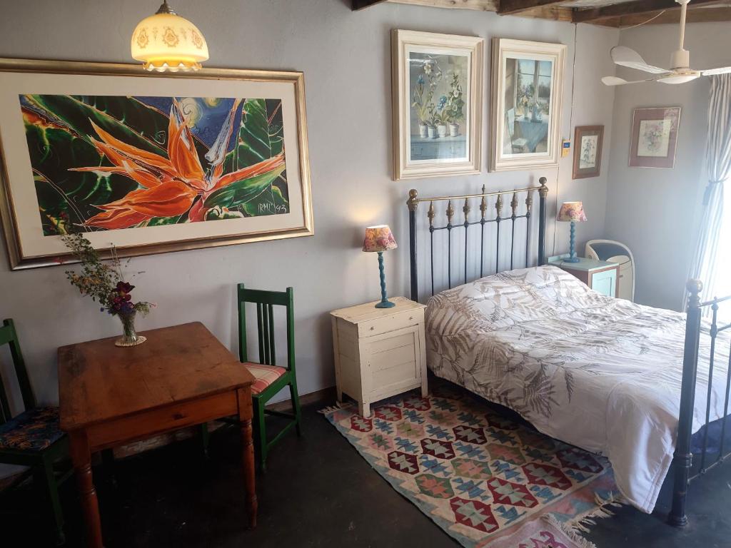 a bedroom with a bed and a table and a painting at Cottage on Roux in Smithfield