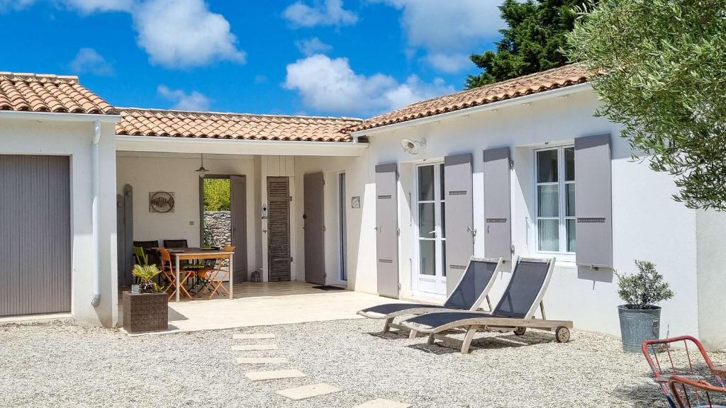 een wit huis met 2 stoelen op een patio bij Au lieu dit La Passe , Villa individuelle de plain pied, avec beaucoup de charme in La Couarde-sur-Mer