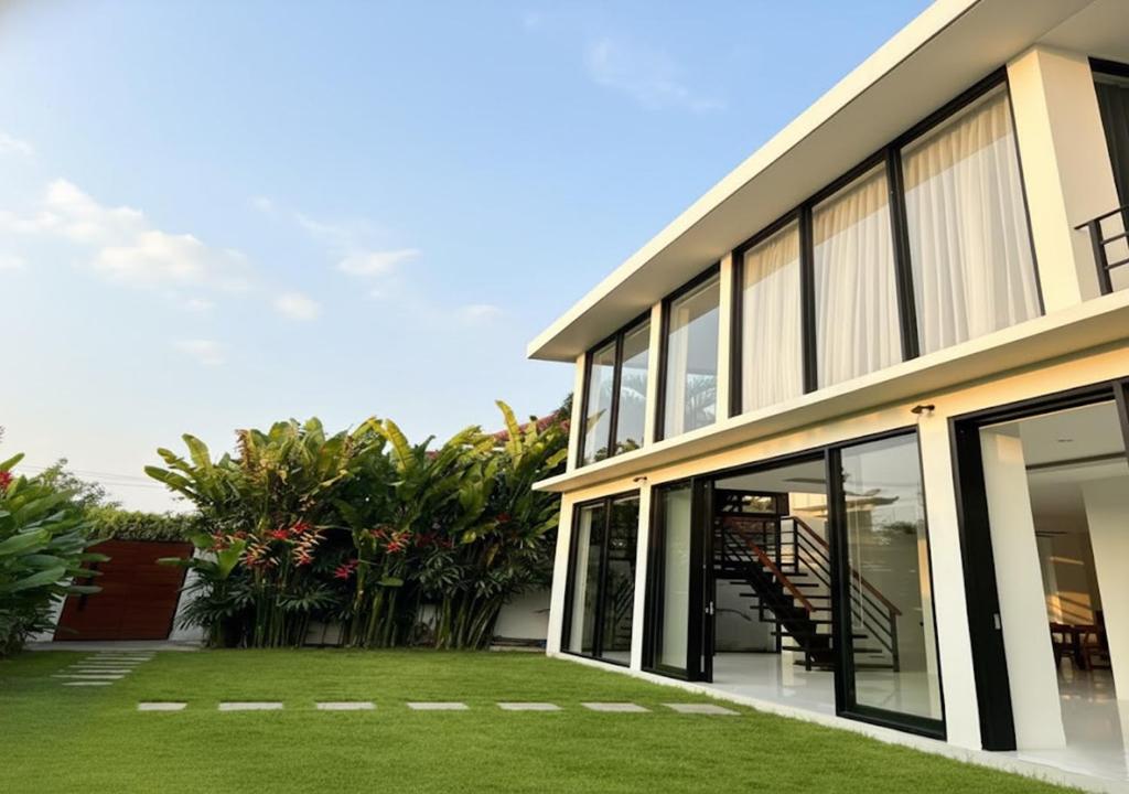 une maison avec de grandes fenêtres et une pelouse dans l'établissement Luxury 3BR Villa Noeul With Private Pool 5min To Seminyak Beach, à Seminyak