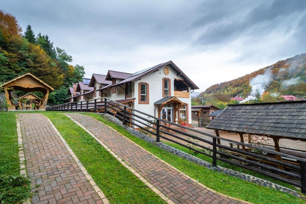 a house with a fence next to a brick road at Pensiunea Popas Pop, Strambu-Baiut, Maramures in Băiuţ