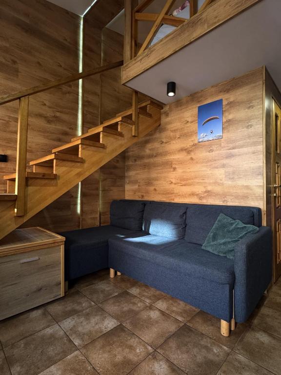 - un salon avec un canapé bleu et des escaliers dans l'établissement Odlotowe noclegi, à Chełmno