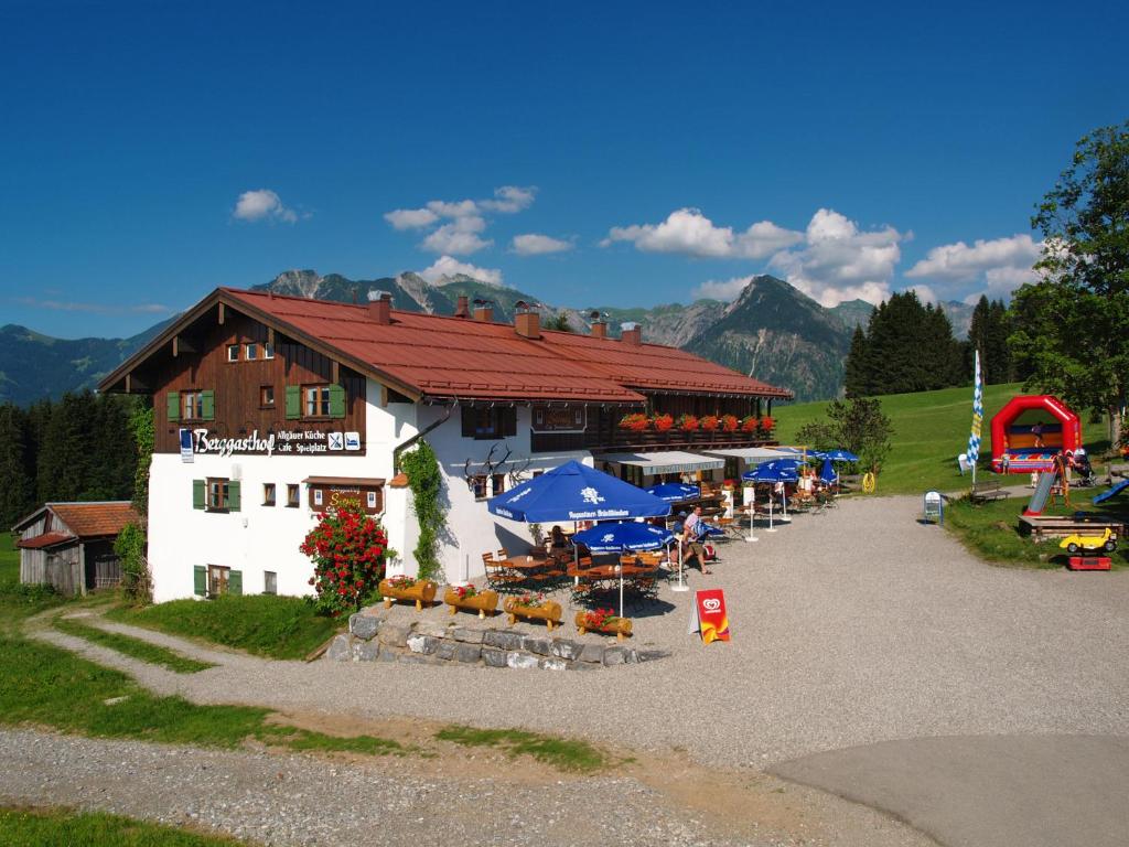 a building with tables and umbrellas in front of it at Gasthof Seeweg in Oberstdorf