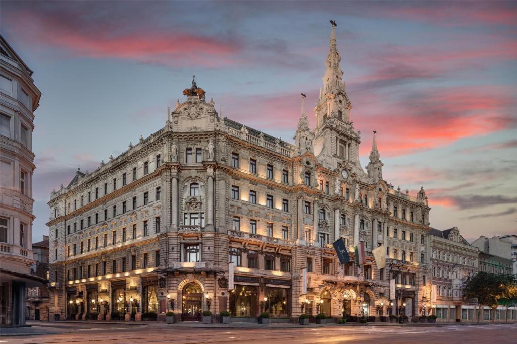 a large building on a street with a sunset at Anantara New York Palace Budapest - A Leading Hotel of the World in Budapest