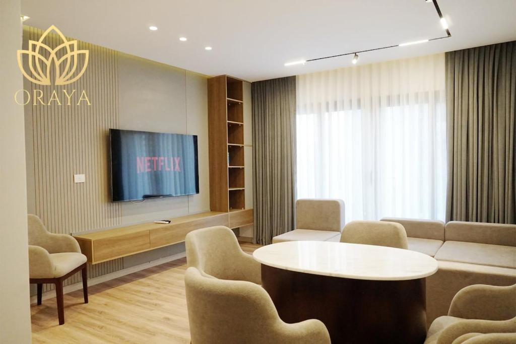 ein Wartezimmer mit einem TV, einem Tisch und Stühlen in der Unterkunft Modern & Bright Getaway in Madinaty in Banī Ghālib