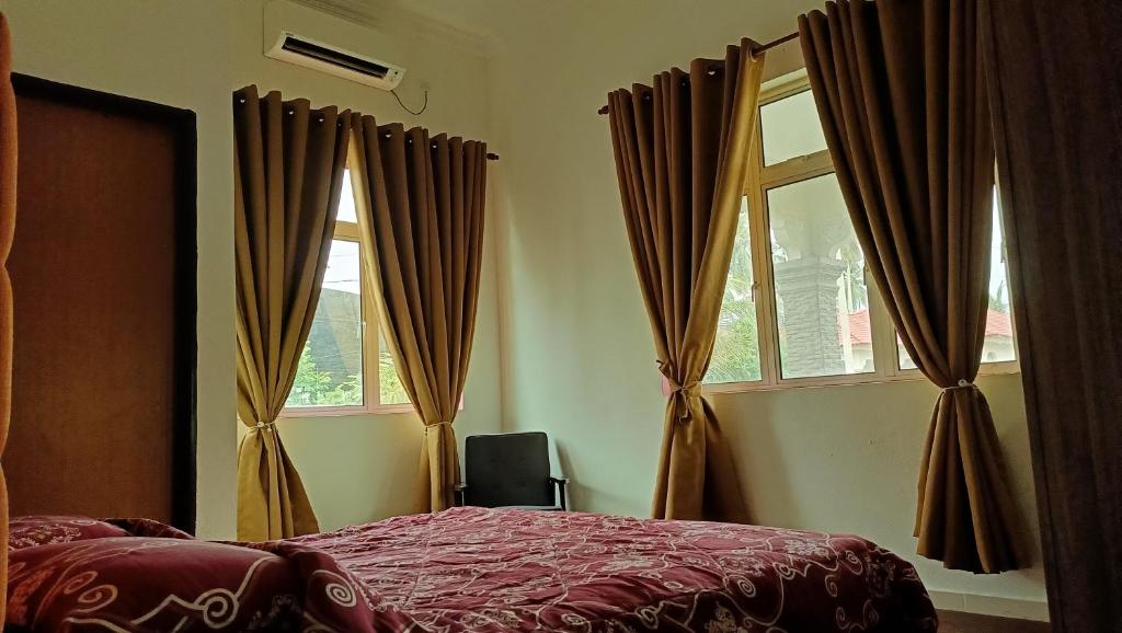 a bedroom with a bed and two windows at Homestay Annur Barakah in Kampung Raja