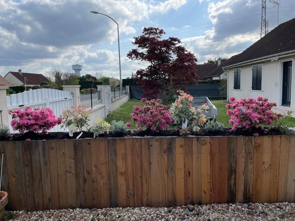 a wooden fence in front of a house with pink flowers at Gîte Aux Portes de Bellevue in Salbris