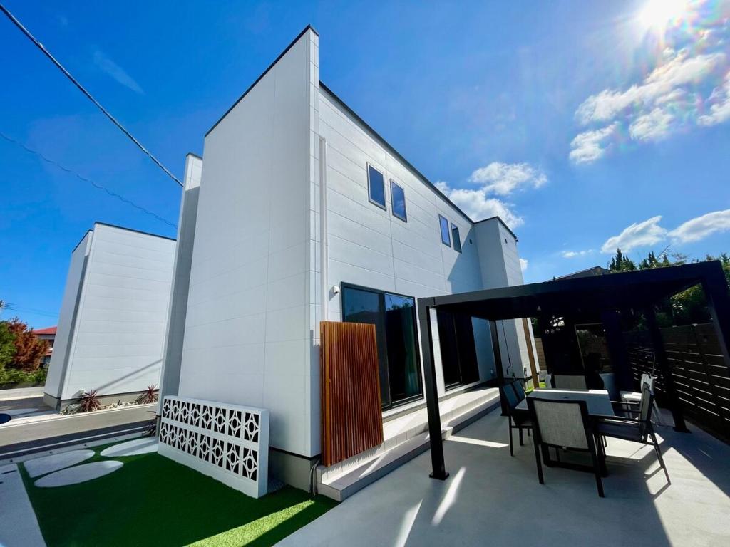 Cette maison blanche dispose d'un balcon avec une table et des chaises. dans l'établissement Lohas Resort 芥屋A, à Itoshima