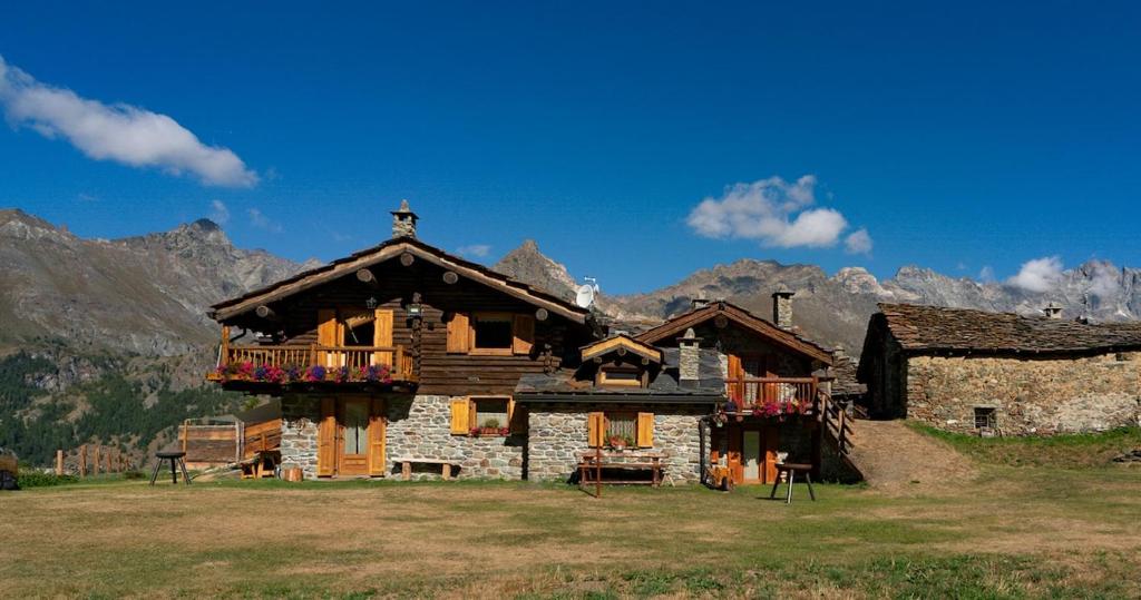 a log house with a balcony and mountains in the background at Le Mayen in Valtournenche
