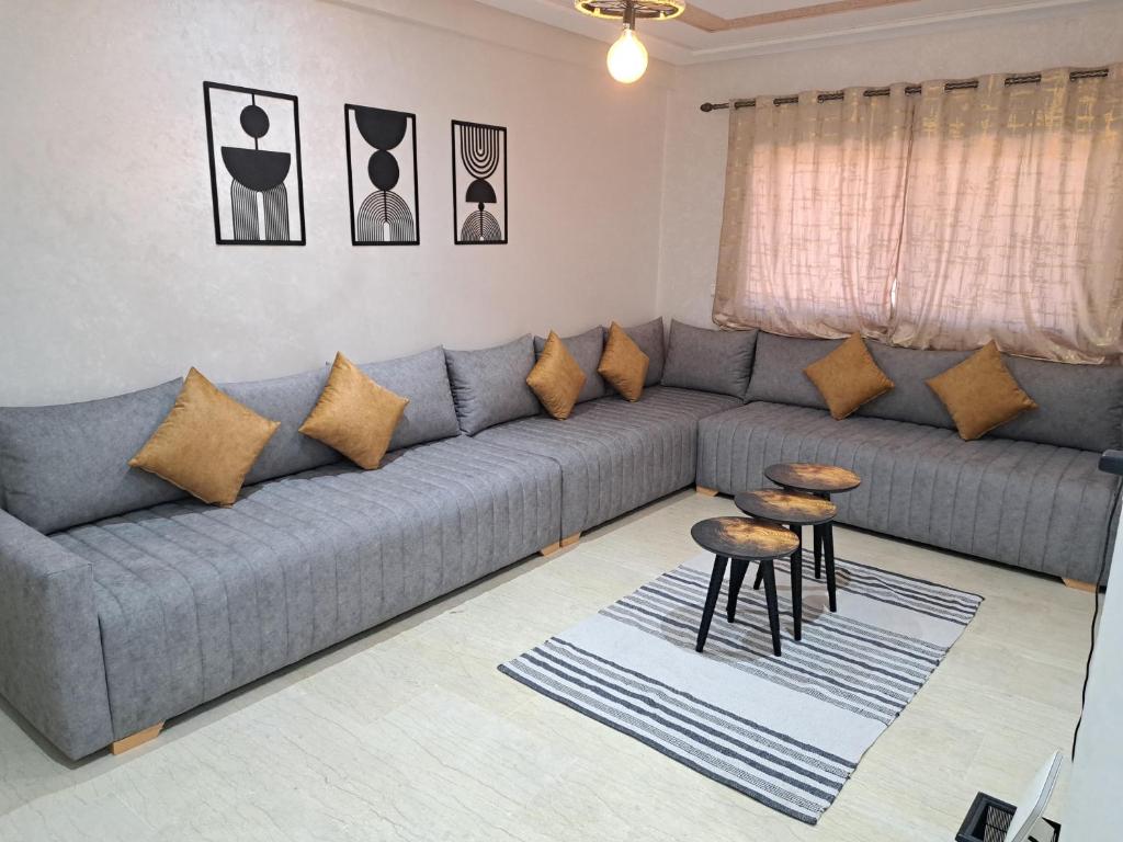 uma sala de estar com um sofá cinzento e duas mesas em Appartement Au Centre Ville Prés de la Medina em Fez