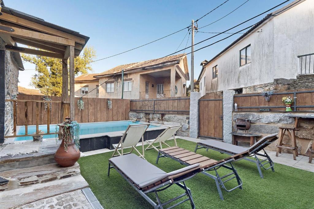 a patio with two chairs and a swimming pool at Casas da Chica com Piscina, Arouca in Espiunca