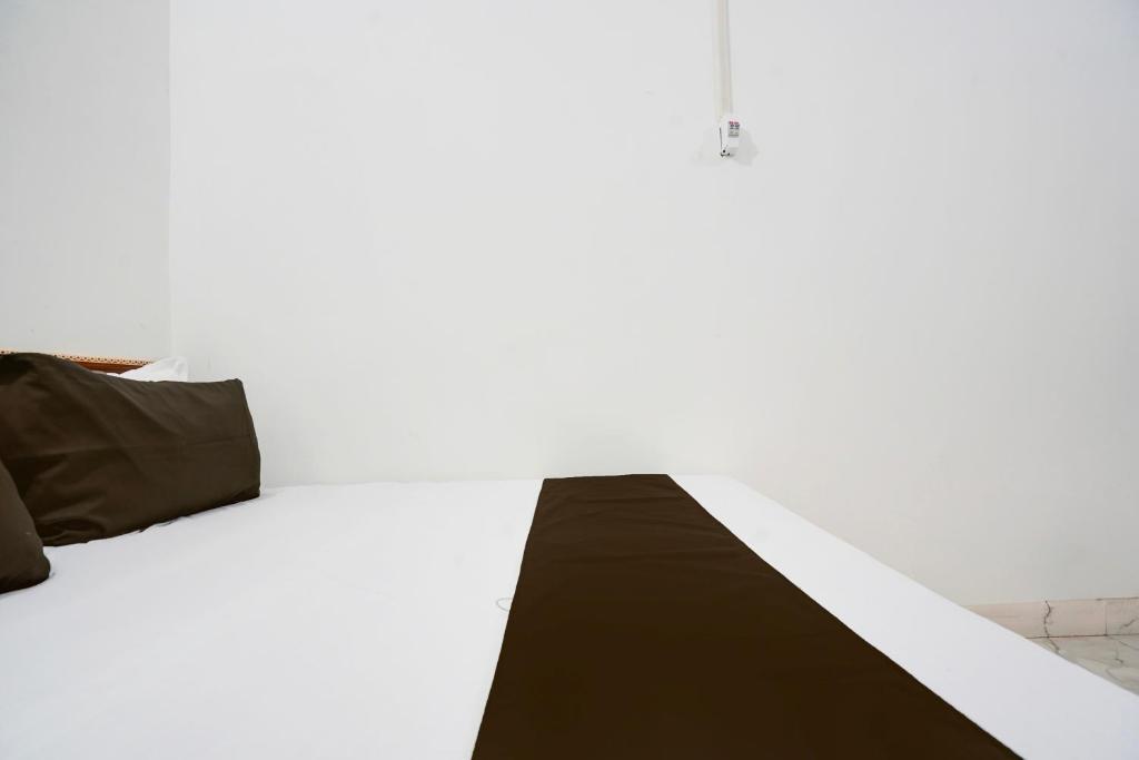 a bed with black and white sheets and pillows at OYO 82207 KRISHNA GUEST HOUSe in Bulandshahr