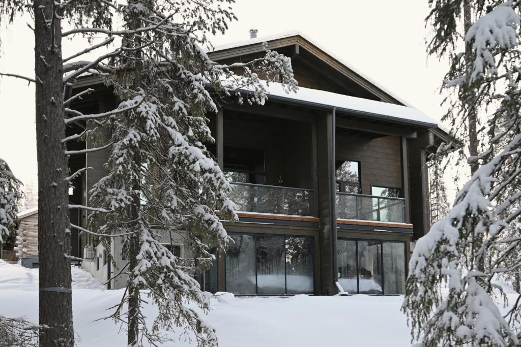a log cabin in the snow with snow covered trees at Villa Taruilevi 3 inc Hot Tub in Levi