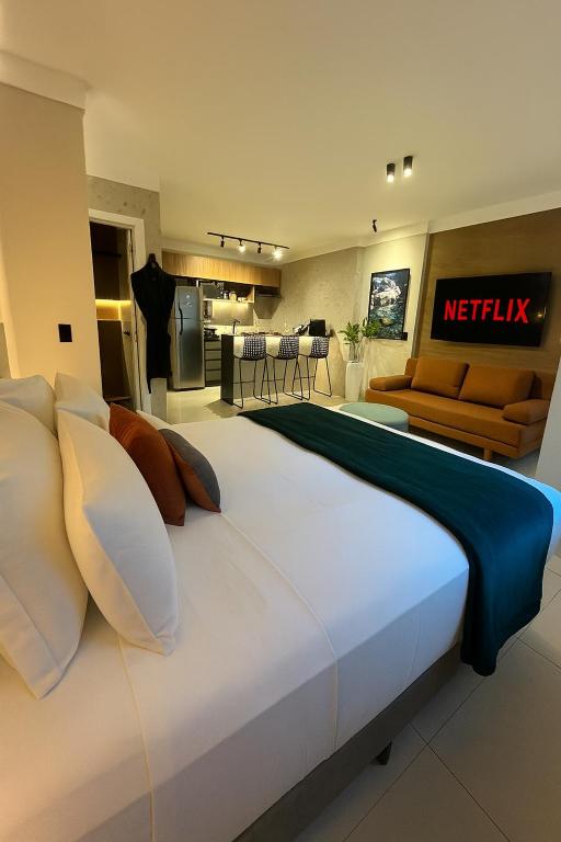 a large white bed in a room with a kitchen at Flat Praia Comfort Camburi in Vitória