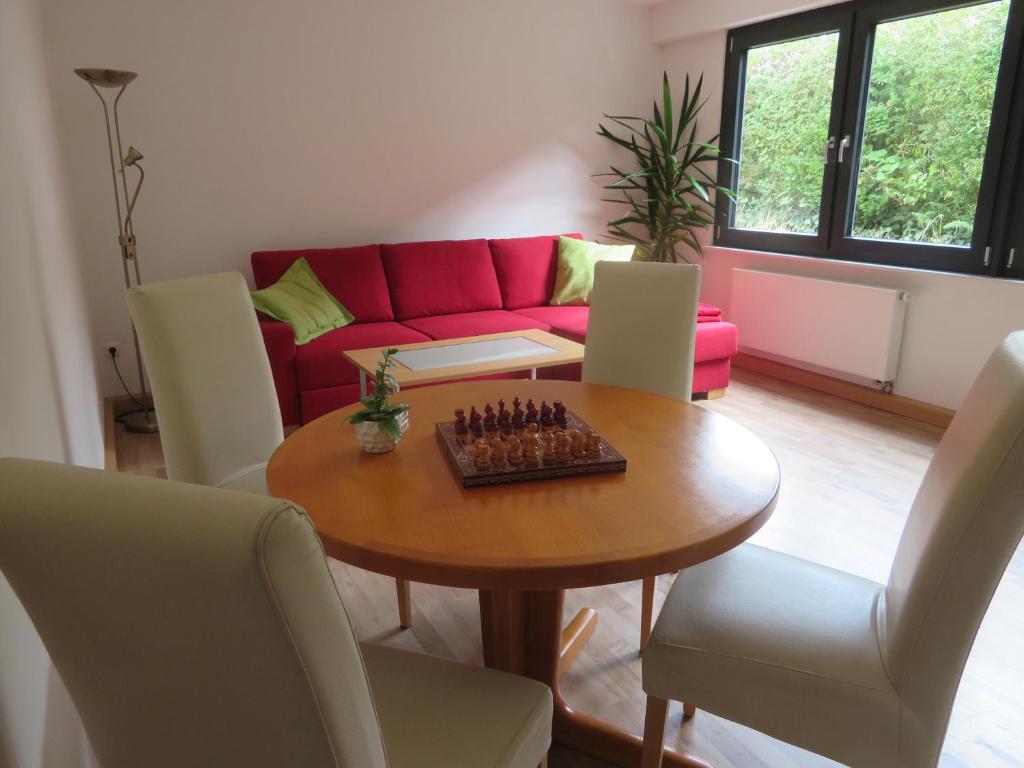 a living room with a table and a red couch at Ferienwohnung Vollmarshausen in Lohfelden