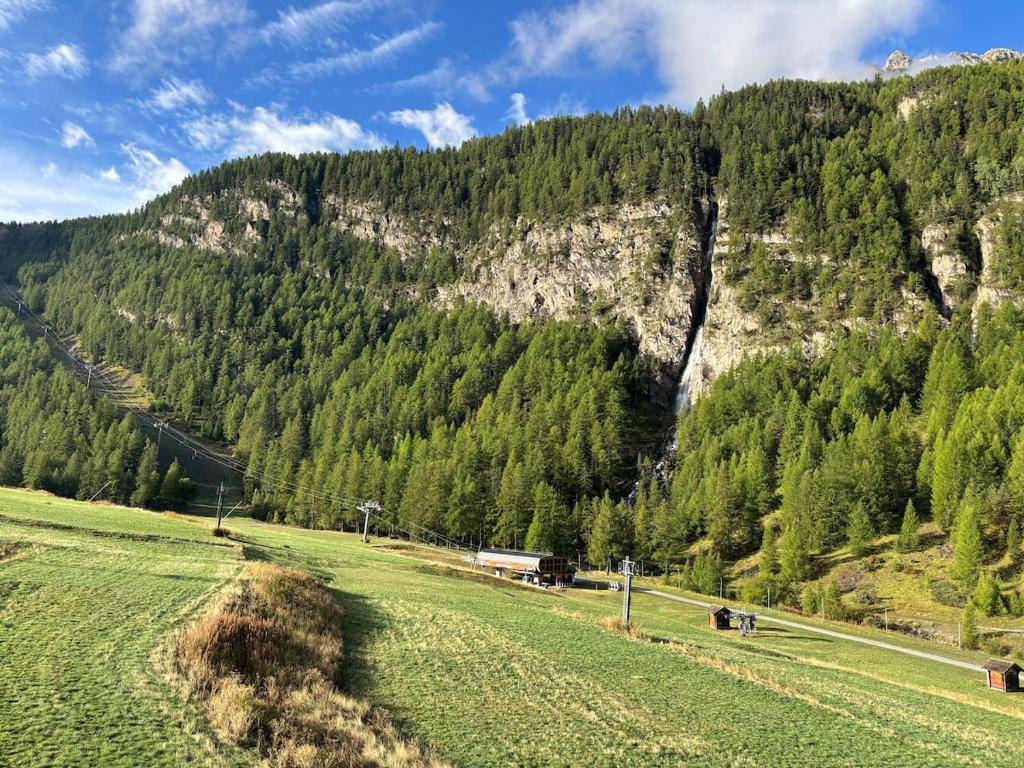 a grassy field in front of a mountain at Appartement cosy entre lacs et montagnes in Guillestre