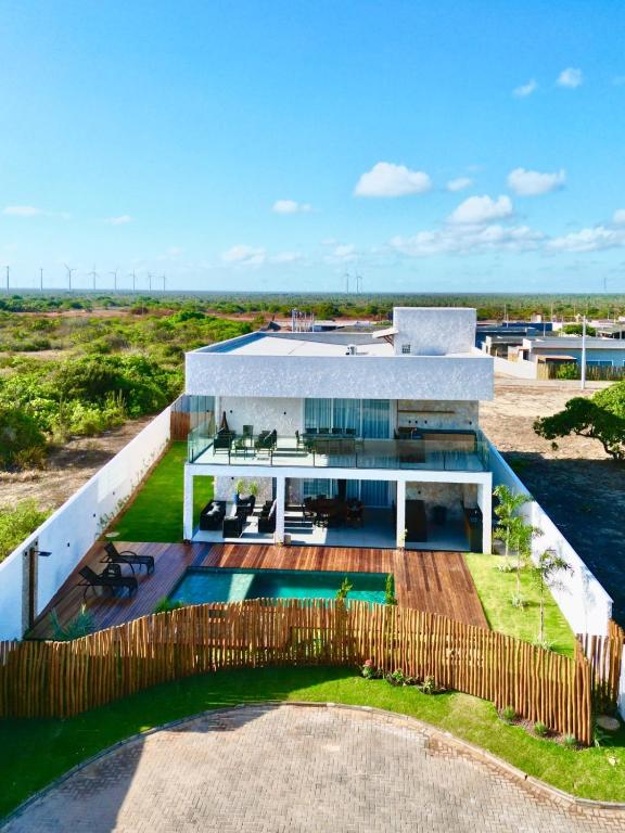 a house with a swimming pool and a wooden fence at Uhane Grand Villa 7 Quartos, Piscina e Vista Mar in São Miguel do Gostoso