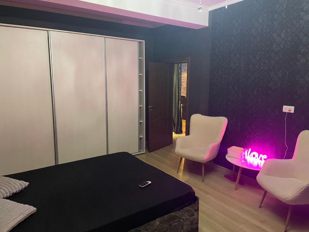 Una habitación con dos sillas y una mesa con una luz rosa. en Magical Desire, en Bragadiru